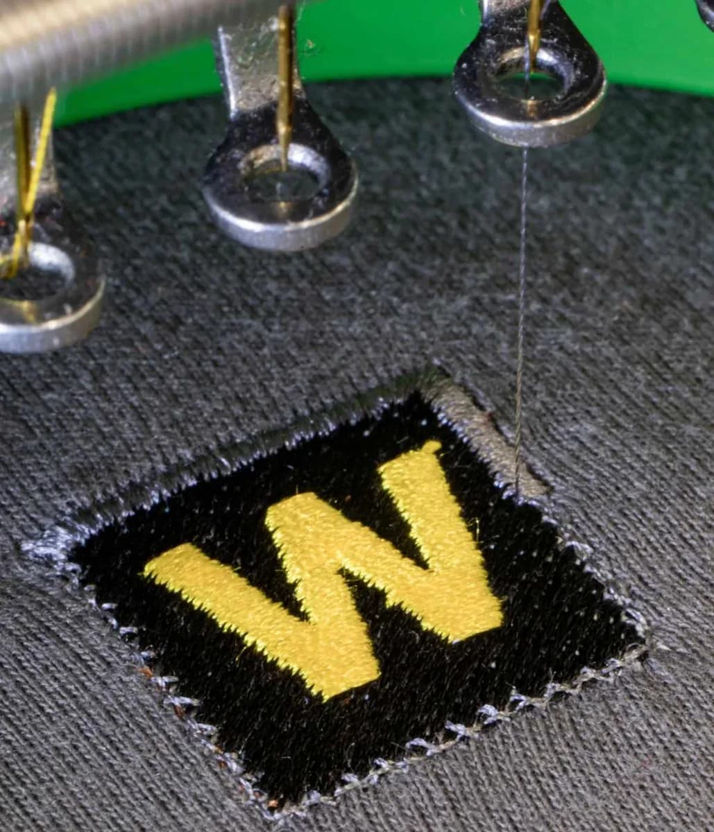 Industrial embroidery machine stitching company logo onto workwear — embroidery Guildford